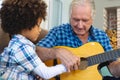 Caucasian senior man teaching playing guitar to biracial grandson while sitting at home Royalty Free Stock Photo