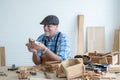 Caucasian senior old white bearded man carpenter in apron and hat working in workshop, holding and looking at handmade wood toy, Royalty Free Stock Photo