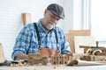 Caucasian senior old white bearded man carpenter in apron, hat working in workshop, use pencil sketching a design on paper, Royalty Free Stock Photo