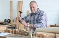 Caucasian senior old white bearded man carpenter using hammer and chisel working in workshop, tools machine small wooden toy model Royalty Free Stock Photo