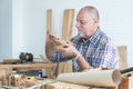Caucasian senior old white bearded man carpenter working in workshop, use sandpaper polishing a wood car toy, tools machine and Royalty Free Stock Photo