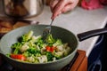 caucasian senior woman hand with fork picks frying vegetables in frying pan Royalty Free Stock Photo