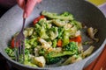 caucasian senior woman hand with fork stirring frying vegetables in frying pan Royalty Free Stock Photo