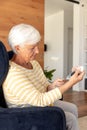 Caucasian senior woman measuring her blood sugar using glucometer at home