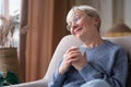 Caucasian senior woman relaxing drinking cup of tea in armchair at home Royalty Free Stock Photo