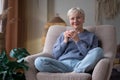 Caucasian senior woman relaxing drinking cup of tea in armchair at home Royalty Free Stock Photo