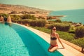 Caucasian skinny model with thin waist relaxing in luxurious infinity pool. Young woman rest in spa resort. Summer luxury vac Royalty Free Stock Photo