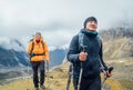 Caucasian and Sherpa men backpackers with trekking poles together hiking and enjoying Mera peak climbing acclimatization walk