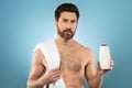 Caucasian shirtless man showing shampoo bottle, shower gel or body lotion, advertising male cosmetic product Royalty Free Stock Photo