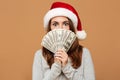 Caucasian shocked lady wearing christmas hat holding money.