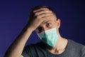 Caucasian sick man in a medical gause mask with palm on his head Royalty Free Stock Photo