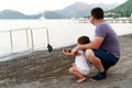 Caucasian small girl with dad with selfie stick on the seaside. Taking photo, recording vlog, video call Royalty Free Stock Photo