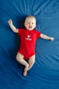 Caucasian smiling baby boy girl with blue eyes lying on bed at home on Canada Day Royalty Free Stock Photo