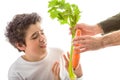 Caucasian smooth-skinned boy holds hands to reject carrot and ce