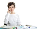 Caucasian smooth-skinned boy talking on cell phone on homeworks Royalty Free Stock Photo