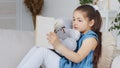 Caucasian spaniard school girl child kid daughter pupil sitting on couch sofa at home in living room interior hugging