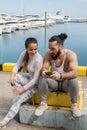 Couple listening to music together using one earphones sitting on pier Royalty Free Stock Photo