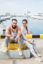 Couple listening to music together using one earphones sitting on pier Royalty Free Stock Photo