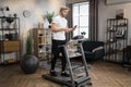 Caucasian sportsman having online video class training on smartphone using treadmill Royalty Free Stock Photo