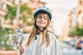 Caucasian sporty teenager girl wearing bike helmet and drinking bottle of water at the city Royalty Free Stock Photo