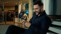 Caucasian stylish man in black suit successful businessman customer sit at shopping mall using mobile phone apps make Royalty Free Stock Photo