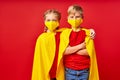 Caucasian superhero children in medical masks isolated on red background Royalty Free Stock Photo