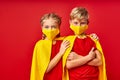 Caucasian superheroes kids in medical masks isolated on red background Royalty Free Stock Photo