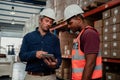 Caucasian supervisor explaining tips for improvement to ethnic worker in factory shop.