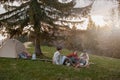 Caucasian team of friends hikers resting with guitar playing at tent in mountains. .