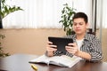 Caucasian teen boy learning language online using digital tablet, doing school tasks at home. E-learning concept