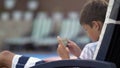 Caucasian teen boy lying on lounger operating mobile phone at swimming pool Royalty Free Stock Photo