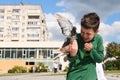 Teenage boy feeding rock pigeons outdoors. The concept of kindness, love and care for animals Royalty Free Stock Photo