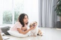 Caucasian teenage girl playing with shih tzu puppy dog at home with love. Young woman lying on floor, feeding food to Royalty Free Stock Photo