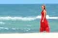 Blond girl with red dress walking on beach Royalty Free Stock Photo