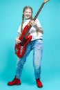 Caucasian Teenager Guitar Player With Red Shiny Bass Guitar Posing In Casual White Shirt Showing Pleased Expression On Turquoise