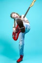 Caucasian Teenager Guitar Player With Red Shiny Bass Guitar Posing In Casual White Shirt Showing Stage Scenic Expression On