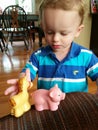 Little blonde boy playing with plastic silicone animals. Royalty Free Stock Photo