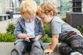 Caucasian toddlers boys sitting together and playing games on cell mobile phone digital tablet Royalty Free Stock Photo