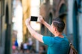 Caucasian tourist with smartphone in hands walking along the narrow italian streets in Rome. Young urban boy on vacation Royalty Free Stock Photo