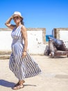 A Caucasian woman walking along an antique Latinamerican marina promenade