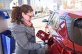 Caucasian white woman at gas station, unscrews the fuel cap of her car to refuel Royalty Free Stock Photo