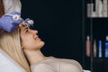 caucasian white woman having iontophoresis face treatment in spa salon on the bed, beauty facial mask.