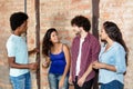 Caucasian woman and african man talking with latin american young adult friends indoors Royalty Free Stock Photo