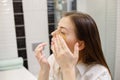Caucasian woman applying hydrogel patches on under eye area, looking at mirror. Happy young lady enjoying morning anti Royalty Free Stock Photo