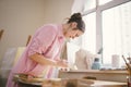 Caucasian woman artist working on a painting in bright daylight studio. Happy artist draws an art project with paints Royalty Free Stock Photo