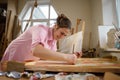 Caucasian woman artist working on a painting in bright daylight studio. Happy artist draws an art project with paints