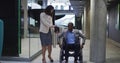 Caucasian woman assists African American man in a wheelchair at the office Royalty Free Stock Photo