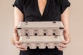 Caucasian woman with black shirt holding two cardboard egg boxes full of chicken eggs. Royalty Free Stock Photo