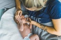 Caucasian woman with blond hair lying in bed with her newborn baby boy caressing his head and letting him suck her thumb Royalty Free Stock Photo