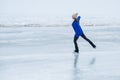 Caucasian woman in a blue sweater is skating on a frozen lake. The figure skater performs the program. Royalty Free Stock Photo